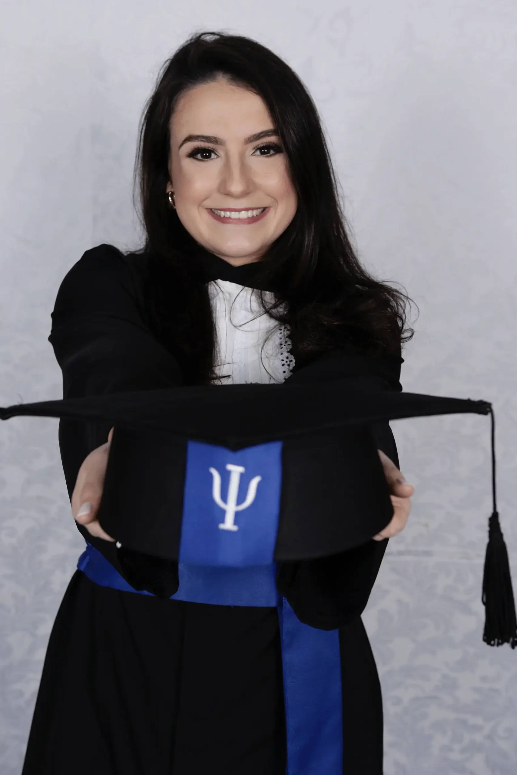 Ana Gabriela Bellaver segurando capelo de formatura com símbolo da Psicologia, celebrando sua graduação pela UFPR e o início de sua trajetória profissional como psicóloga.